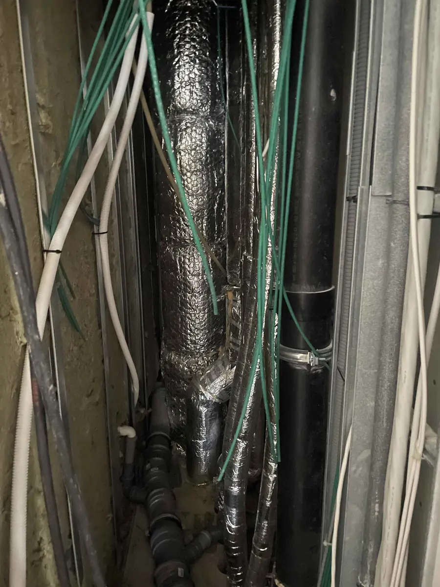 Trang installationsskakt med rør, isolering og kabler